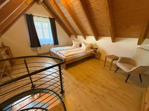 an attic room with a bed and a chair at Ferienwohnungen Am Kirchberg in Neualbenreuth