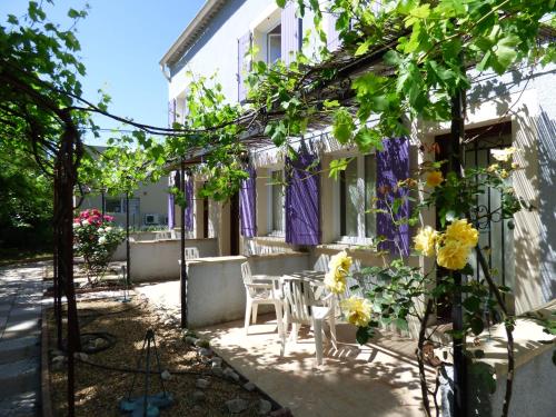 une terrasse d'une maison avec des rideaux violets et des fleurs dans l'établissement Appart'Hotel Festival Sud Aqua - Avignon TGV, à Avignon