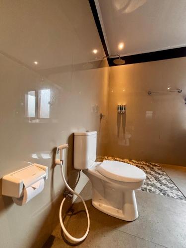 a bathroom with a white toilet and a shower at Qwank Kuta Lombok in Kuta Lombok
