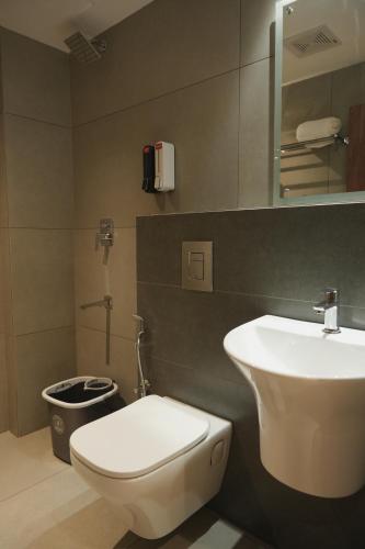 ein Badezimmer mit weißer Toilette und Waschbecken in der Unterkunft Hotel D' Paris in Kozhikode
