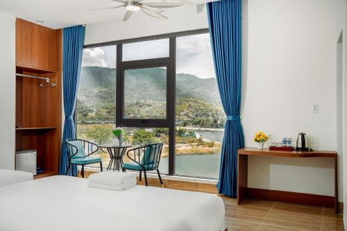 a bedroom with a large window with a table and chairs at Vinh Hy Horizon in Vĩnh Hy