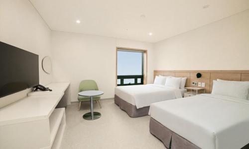 a hotel room with two beds and a tv at Staz Hotel Heritage in Jeju