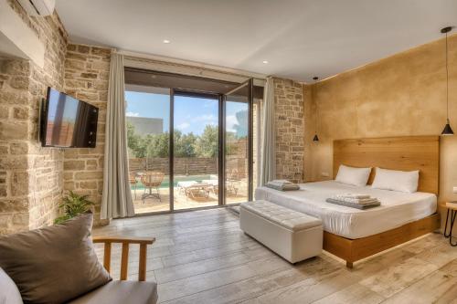 a bedroom with a bed and a large window at Olive Luxury Suites - ADULTS ONLY in Kamilari