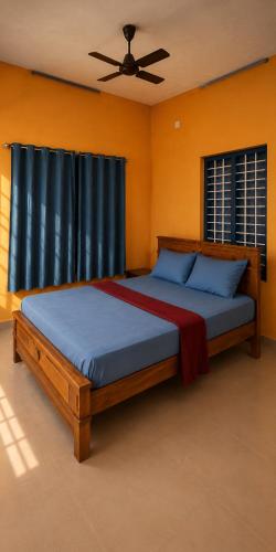 a bedroom with a bed with blue pillows and a ceiling fan at Casa Tangerina in Varkala