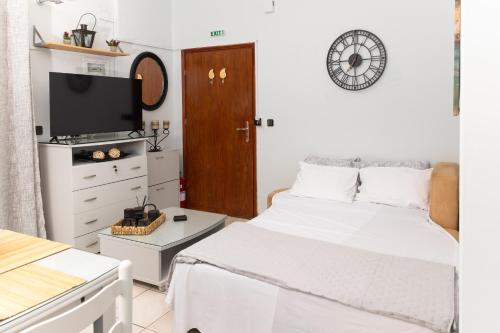 a white bedroom with a bed and a tv at Touzla Blue Heaven in Orfánion