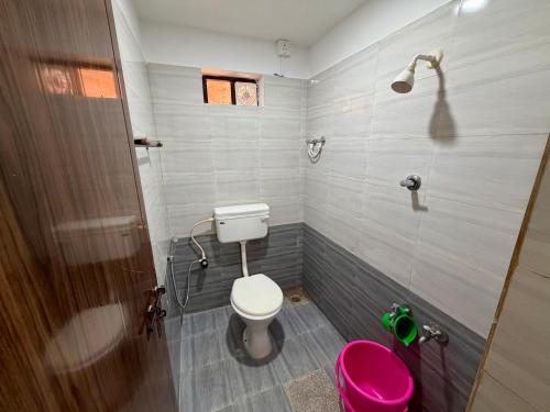 a bathroom with a toilet and a pink stool at AR Cottage in Udupi