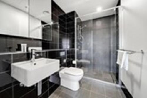 a bathroom with a toilet and a sink and a shower at Chic 1-Bed with Stunning Lake View & Indoor Pool in Belconnen