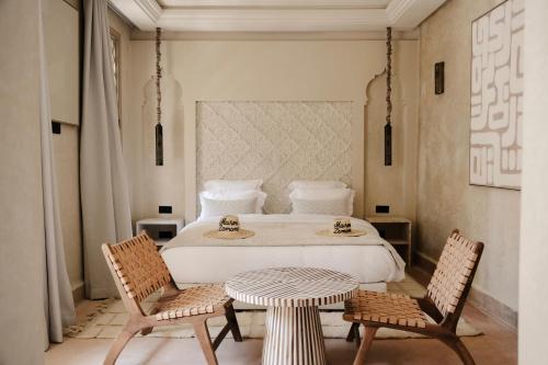 a bedroom with a bed with two chairs and a table at Maison Zamane in Marrakesh