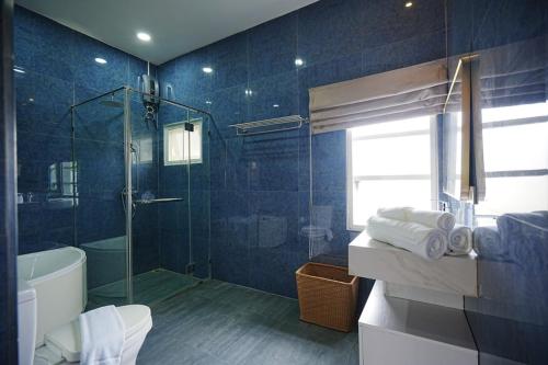 a blue bathroom with a glass shower and a toilet at La Villa des Chien in Ban Nong Chap Tao
