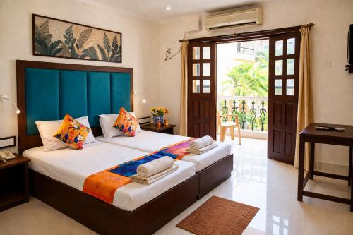 a bedroom with a large bed with a blue headboard at Riverside Regency Resort in Baga