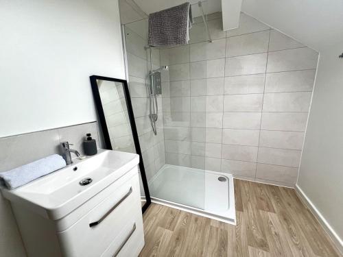 a bathroom with a white sink and a shower at Large Stylish 5 bed Cambridge House in Harston