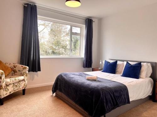 a bedroom with a bed with blue pillows and a window at Large Stylish 5 bed Cambridge House in Harston