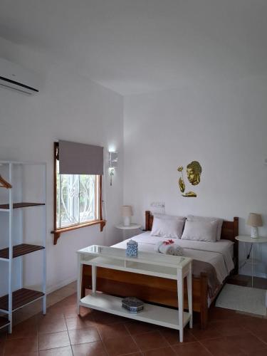a bedroom with a bed and a table and a window at Jay&Kay CosyRoom FlicEnFlac in Flic-en-Flac