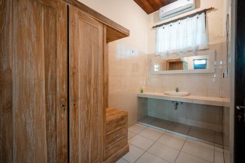 a bathroom with a wooden door and a sink at Bismajaya Bungalow in Ubud