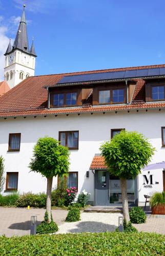 a white building with a clock tower in the background at Hotel Marktliege in Erolzheim