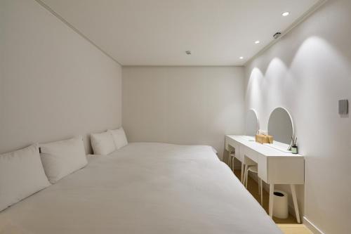 a white room with a bed and a sink at soul stay in Busan