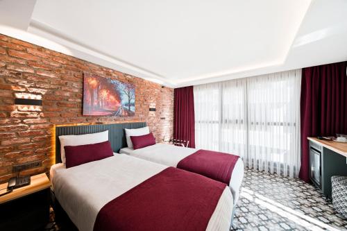 two beds in a room with a brick wall at Taksim Artelist Hotel in Istanbul