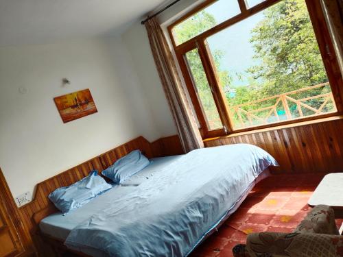 a bed in a bedroom with a large window at Monal House in Manāli