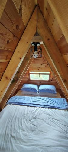 a bed in a wooden attic with a window at Highland Cabins Krnja Jela in Šavnik