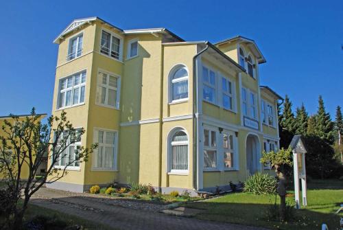 a woman standing in front of a yellow house at Villa Waldblick in Baabe in Baabe