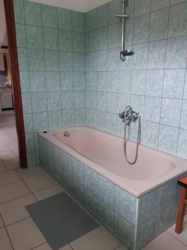 a bath tub in a bathroom with blue tiles at Napsugár Apartman in Szaknyér