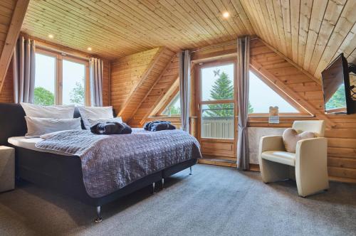 a bedroom with a bed and a chair and windows at Chalets zum Latschen in Mauth