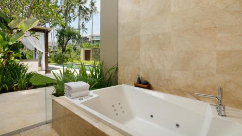 a bath tub in a bathroom with plants at Candi Beach Resort & Spa in Candidasa