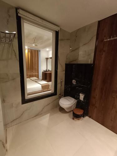 a bathroom with a toilet and a large mirror at RR Hotel & Resort by Sonachi in Dharamshala