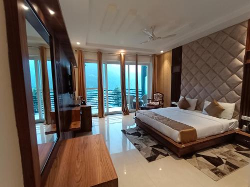 a bedroom with a large bed with a large window at RR Hotel & Resort by Sonachi in Dharamshala