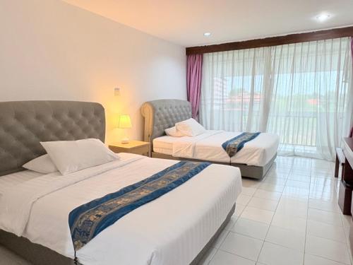 a hotel room with two beds and a window at NJ INTHAI Hotel in Sathani Chiang Rak