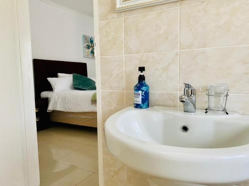 a white sink in a bathroom with a bedroom at Meyrick Bed and Breakfast in Harare