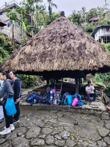 a group of people standing in front of a thatch hut at Ramon's Homestay in Banga-an