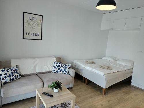 a living room with a couch and a bed at Foliate Living Varpu in Jyväskylä