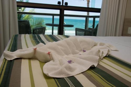 een witte handdoek op een bed met uitzicht op de oceaan bij Namoa Pousada in Cabo de Santo Agostinho