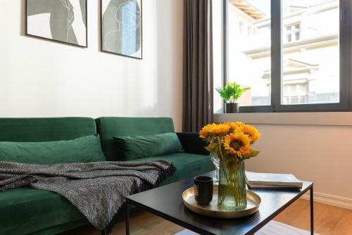 a living room with a green couch and a vase with flowers on a table at Old Town Loft in Tartu