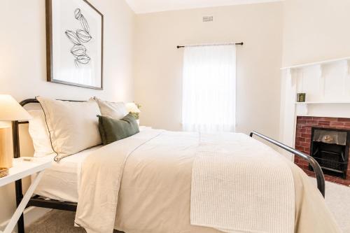 a white bedroom with a bed and a fireplace at Central 3BR Heritage Home Walk to Sovereign Hill & CBD Free Parking in Ballarat