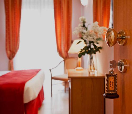 a hotel room with a bed and a vase of flowers at Hotel Kennedy in Rimini
