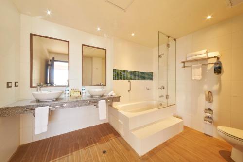 a bathroom with two sinks and a tub and a toilet at Aranwa Paracas Resort & Spa in Paracas