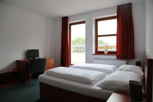 Habitación con 2 camas, escritorio y 2 ventanas. en Sporthotel Hostivice, en Hostivice