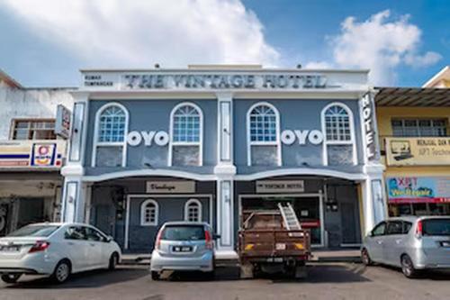 a blue building with cars parked in front of it at Hotel O The Vintage Hotel in Nusajaya