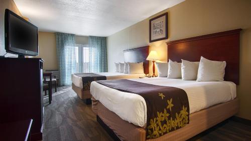 a hotel room with two beds and a flat screen tv at Gold Leaf Hotel of Dewey in Dewey Beach