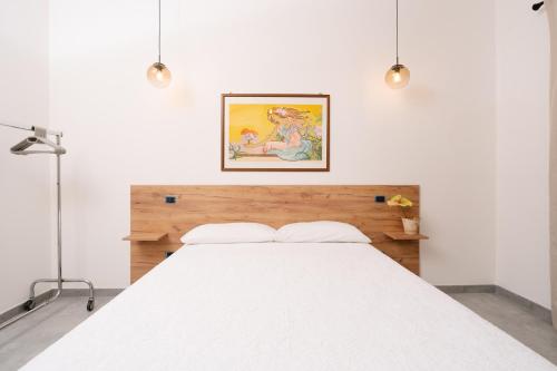 a bedroom with a white bed with a picture on the wall at Case Vacanza Baglio Ciambre in Borgetto