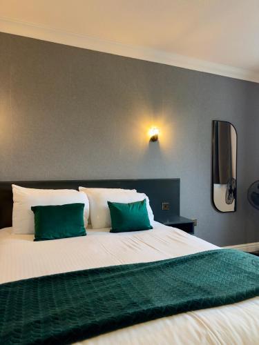a bedroom with a large bed with two green pillows at Hotel Wrexham in Wrexham