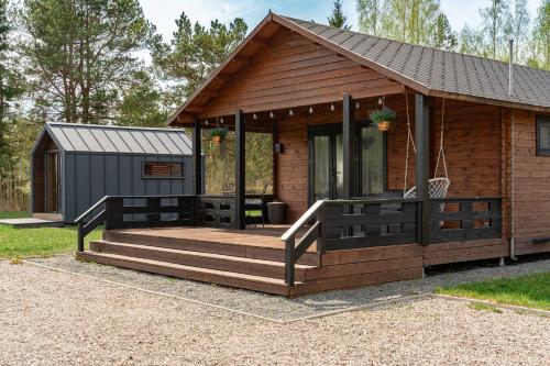 a cabin with a porch and a deck at Forrest Guest House in Ķesterciems