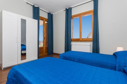 a bedroom with two blue beds and a window at Il Vulcano di Milo in Milo