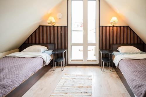 two beds in a room with two tables and a window at Cabin Guesthouse with free parking in Pärnu