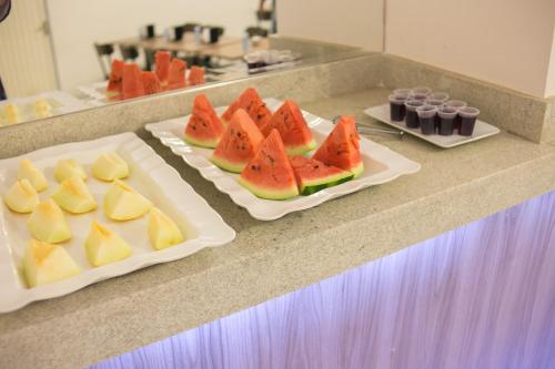 two plates of food on a counter with fruit on them at M & A Hotel in Goiânia