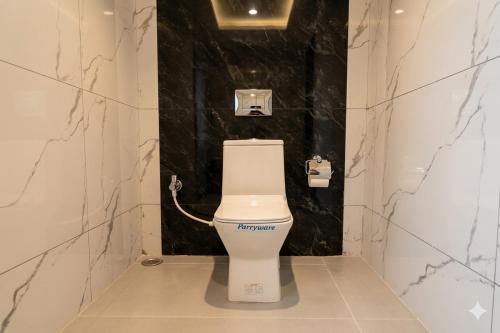 a white toilet in a bathroom with black marble walls at Hotel The Mount View in Rājgīr
