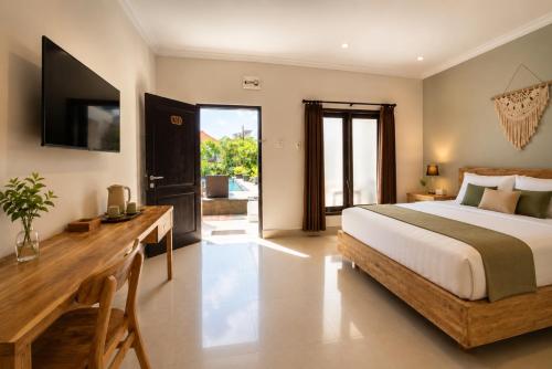 a bedroom with a bed and a desk and a television at Radha Bali Hotel in Kuta