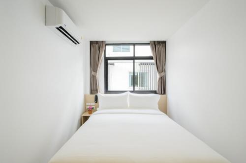 a white bed in a room with a window at Global Hotel Pratunam Bangkok in Bangkok